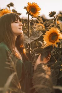 Young woman closing eyes in sunflowers